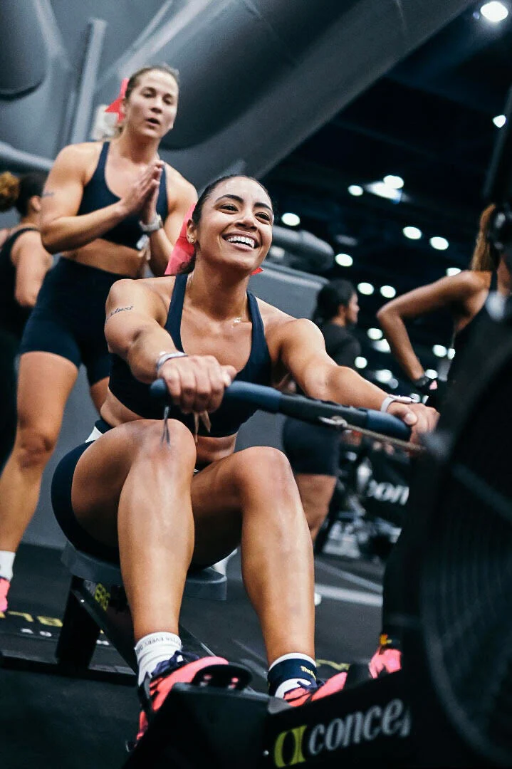 Angel, co-founder of Angel Dust, competing on a rowing machine at a Hyrox event